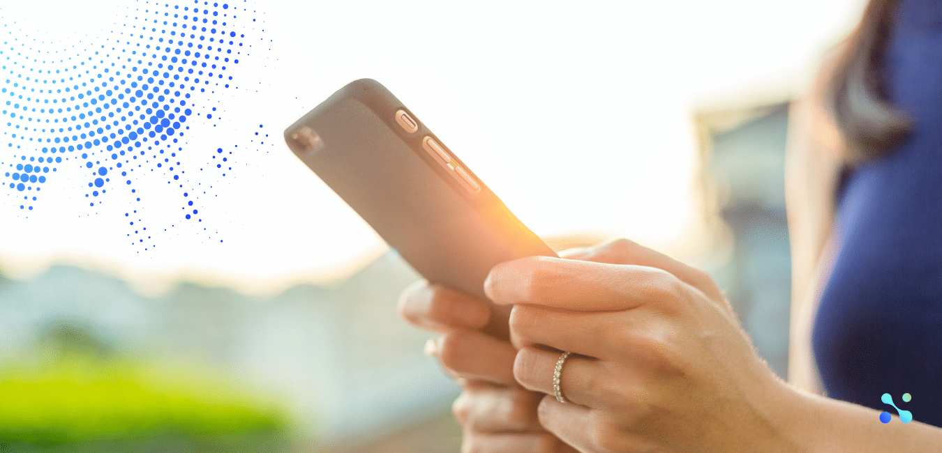 Close-up of a person holding a smartphone in sunlight, symbolizing the role of blockchain in shaping the future of business and finance.